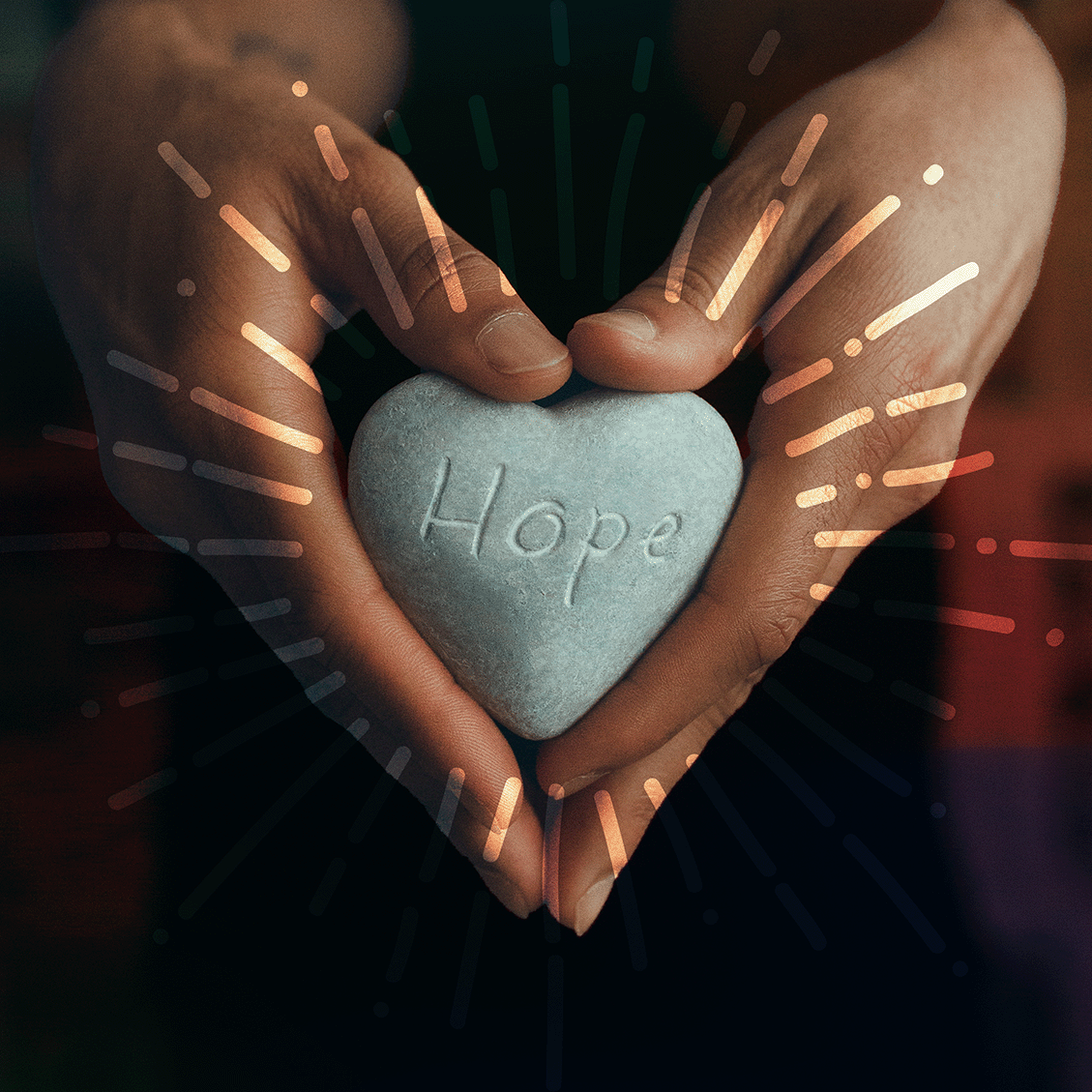 hands hold a heart shaped stone with the word Hope carved on